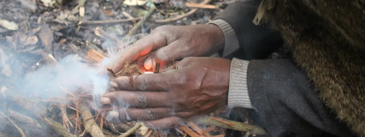 Elder Samuel adding kindling to the flame in traditional fire-making tutorial